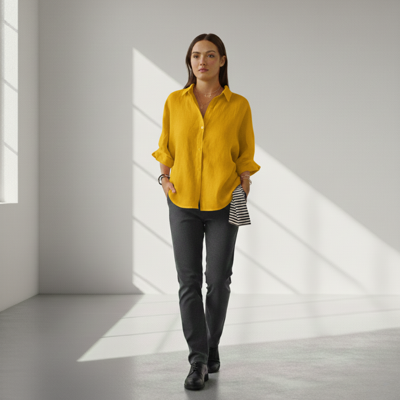 Woman wearing a yellow shirt and gray pants in a bright room with sunlight filtering through.