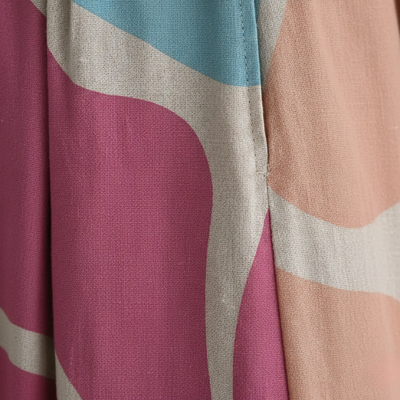 Close-up of fabric with abstract pattern in pink, blue, and beige.
