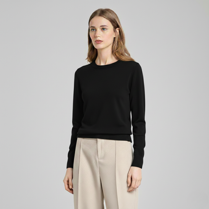 Model wearing a black knit sweater in a minimalist studio, featuring a timeless women’s crewneck style.