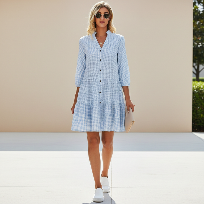 Woman wearing a blue checkered dress with white sneakers on a neutral background
