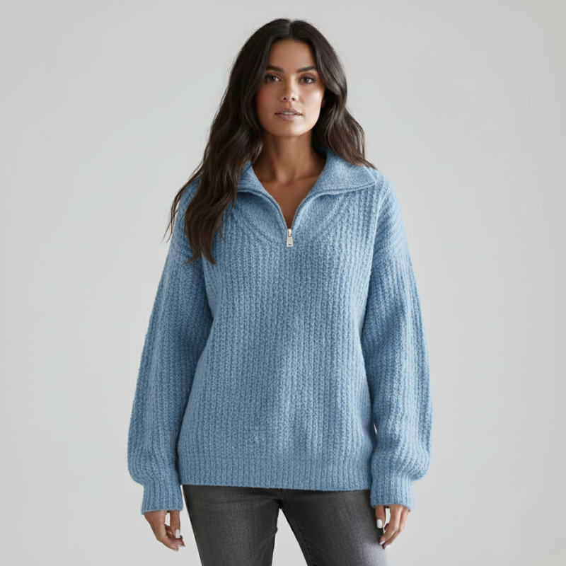 Hellblauer Strickpullover mit halbem Reißverschluss, lockerer Passform und strukturierter Oberfläche im Studio.