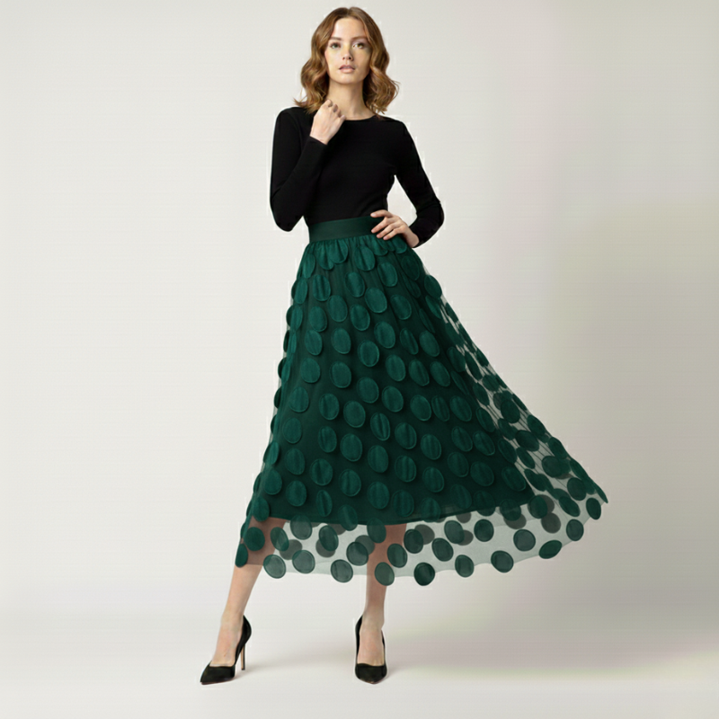 Woman wearing a black top and green skirt with a floral pattern on a white background