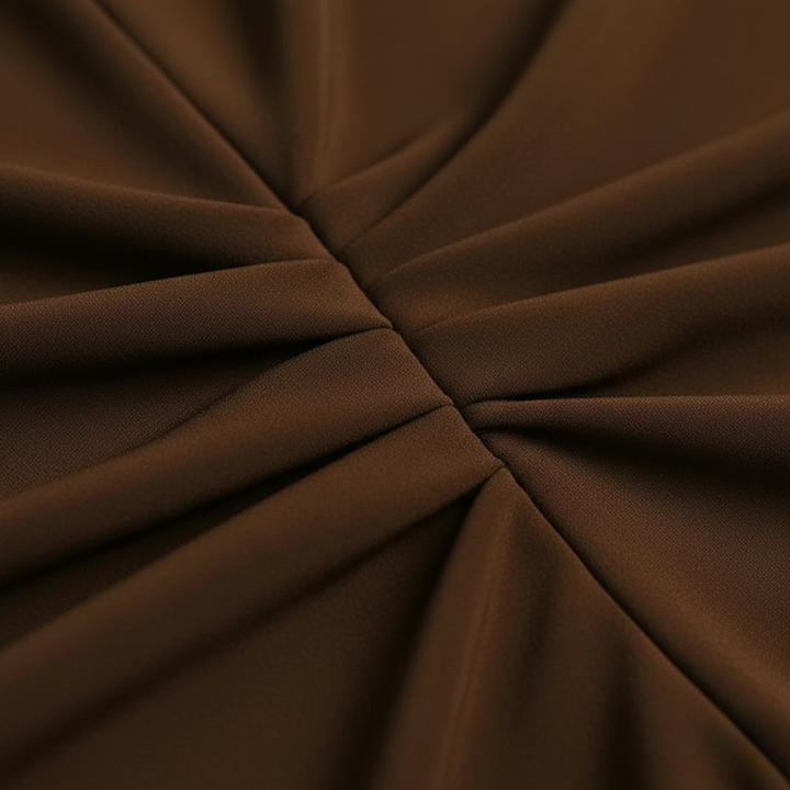 Close-up of brown dress fabric showing ruched detailing and soft texture.