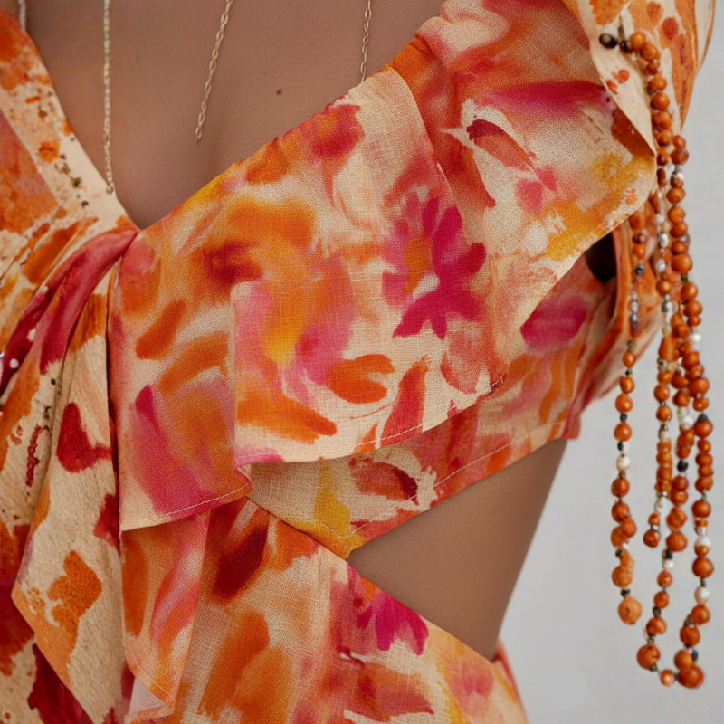 Close-up shot of the orange floral maxi dress showing ruffled neckline, floral fabric texture, and tie-strap detailing.