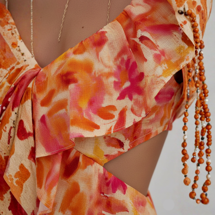 Close-up shot of the orange floral maxi dress showing ruffled neckline, floral fabric texture, and tie-strap detailing.