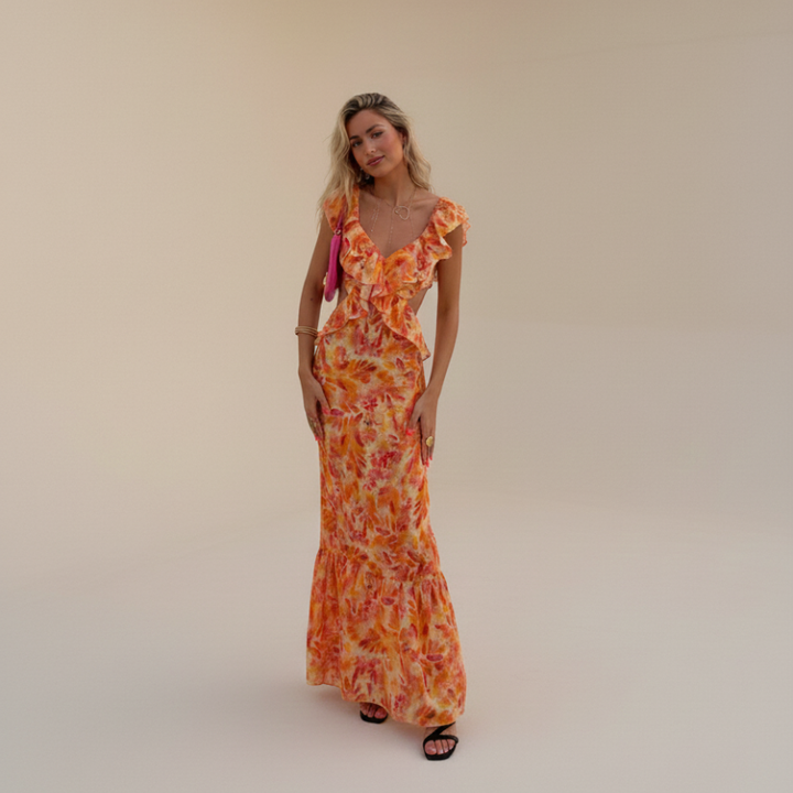 Model standing in a full-body pose wearing an orange printed ruffle maxi dress indoors.