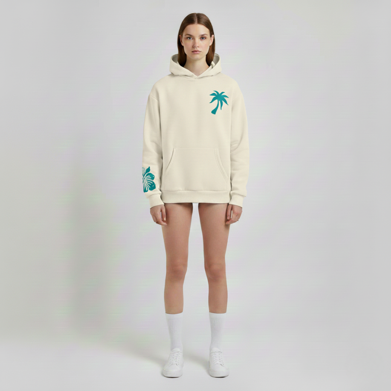 Person wearing a beige hoodie with palm tree designs on a plain background