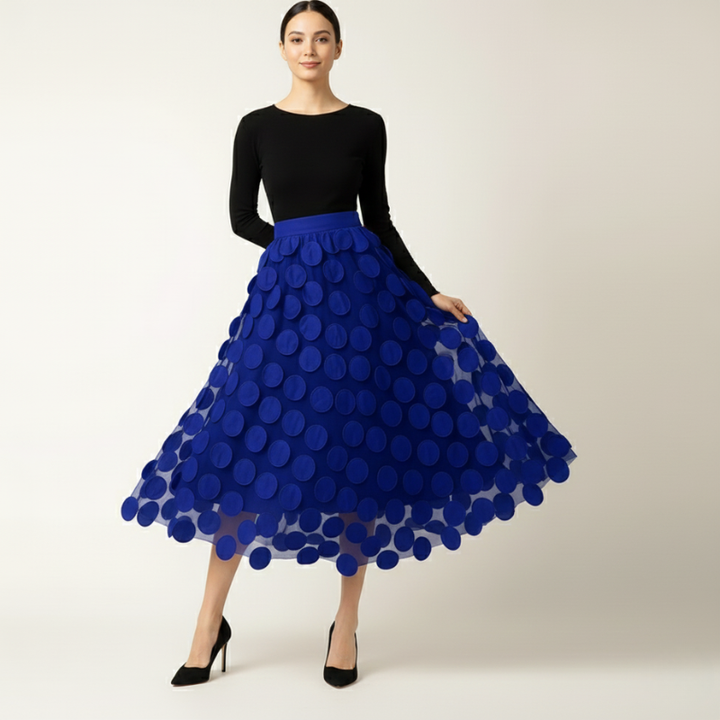 Woman wearing a black top and blue polka dot skirt on a white background