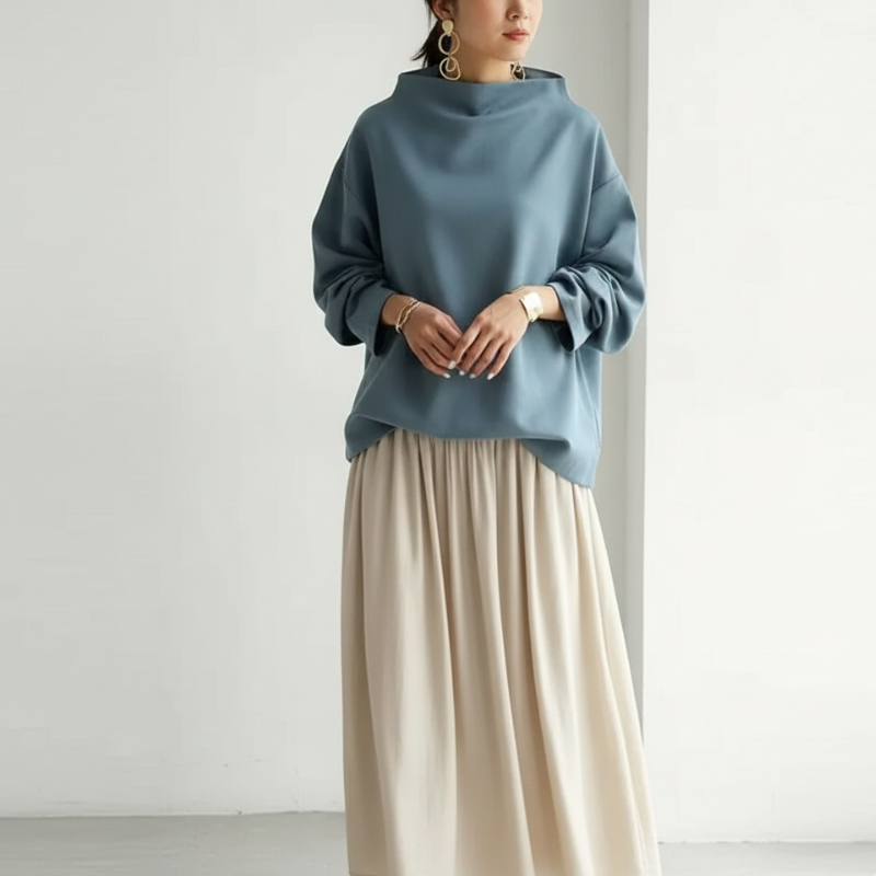 Person wearing a blue sweater and beige skirt against a white background