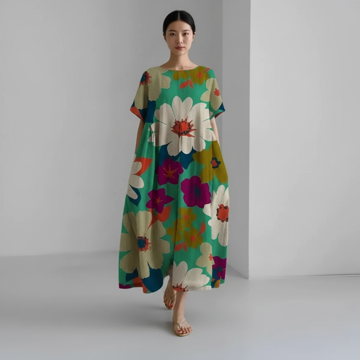 Woman wearing a colorful floral dress against a plain background