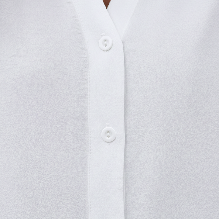 Close-up of the white blouse showing button placket, smooth fabric texture, and clean stitching details.