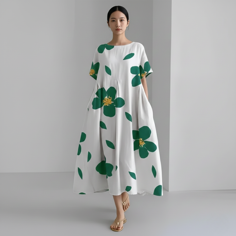 Woman wearing a white dress with green floral patterns against a plain background