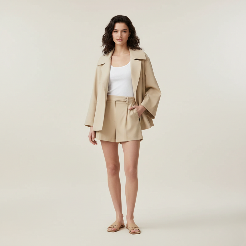 Woman wearing a beige coat and shorts set on a plain background