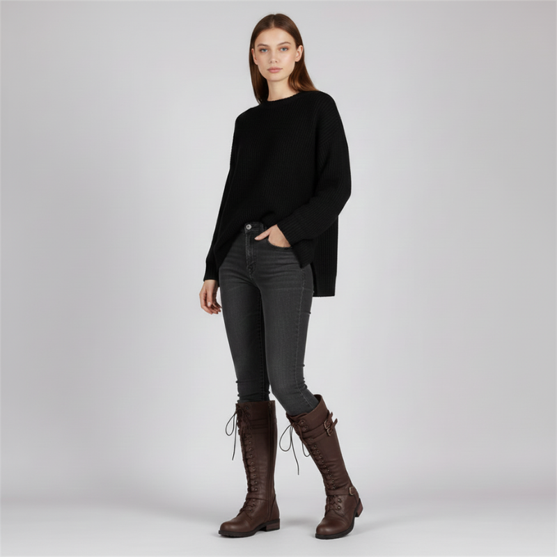 Woman wearing a black sweater, gray pants, and brown boots on a light gray background