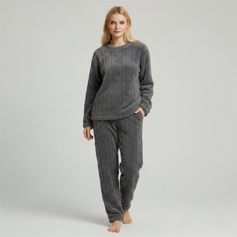 Woman wearing a dark gray fleece lounge set with a soft long-sleeve top and matching pants in a studio setting.