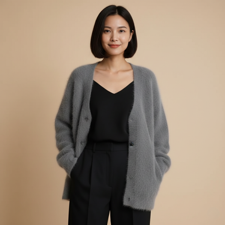 Woman wearing a dark gray knit cardigan layered over a black top in warm indoor lighting.