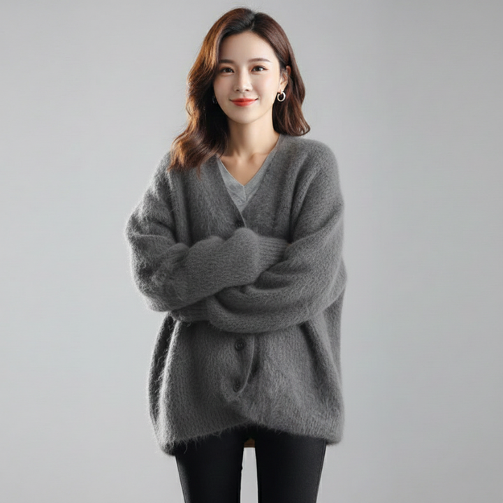 Woman wearing a gray oversized knit cardigan with long sleeves and a relaxed fit in neutral studio lighting.