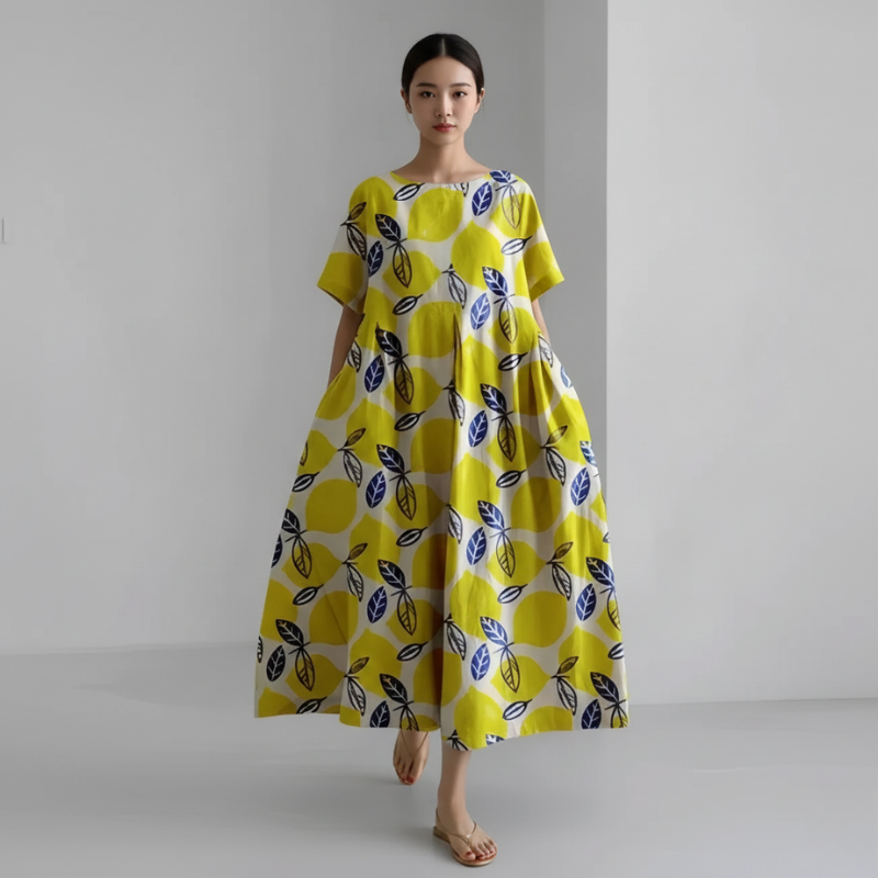 Woman wearing a yellow dress with black leaf pattern on a plain background