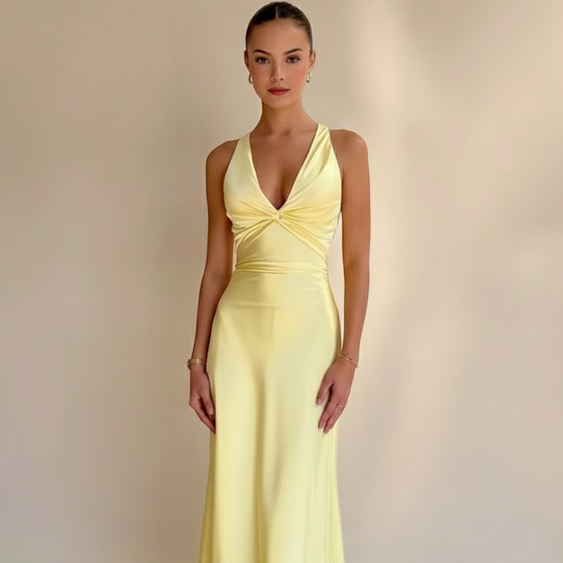 Woman standing in a yellow formal maxi dress with a fitted bodice and floor-length silhouette in a minimal studio setting.