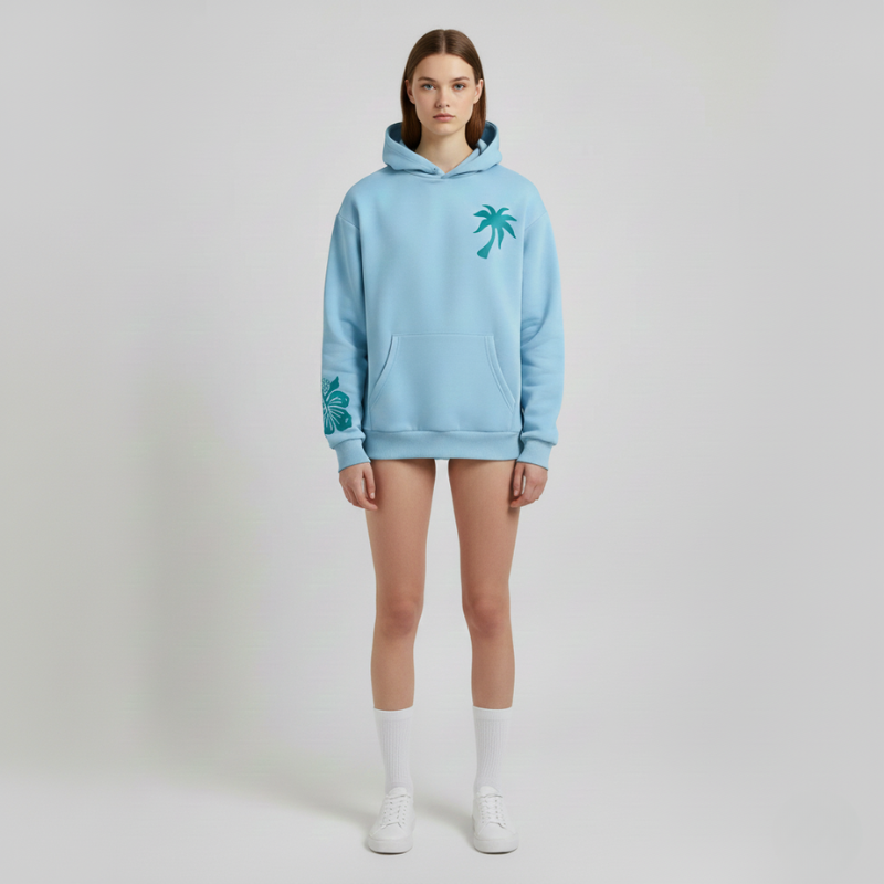 Person wearing a light blue hoodie with palm tree designs on a plain background
